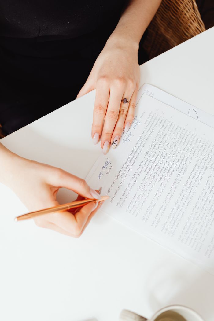 A woman's hands holding a pen over a paper document. Indoor writing scene.